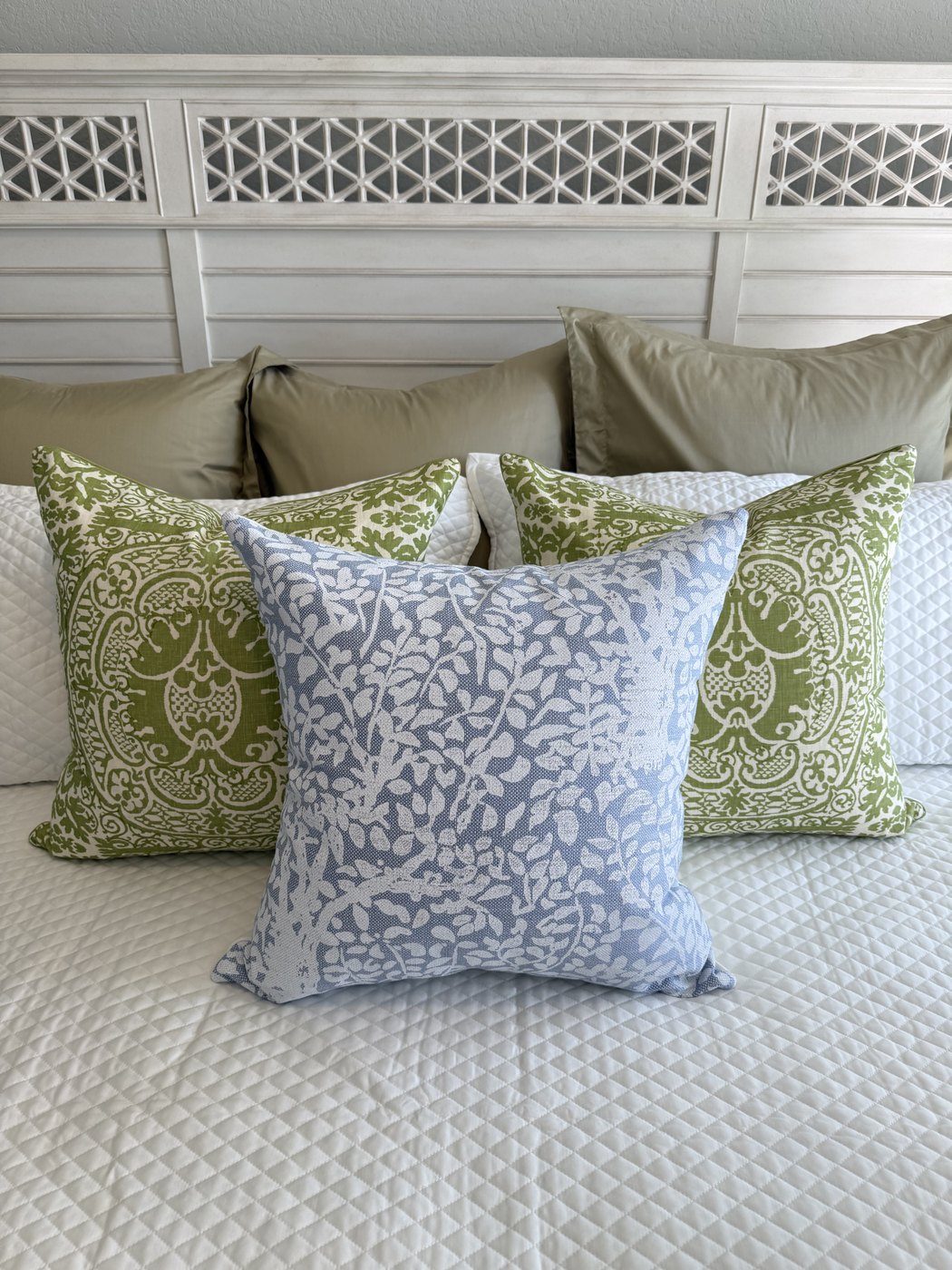 Arbre de Matisse blue pillow with green damask pillows on bed