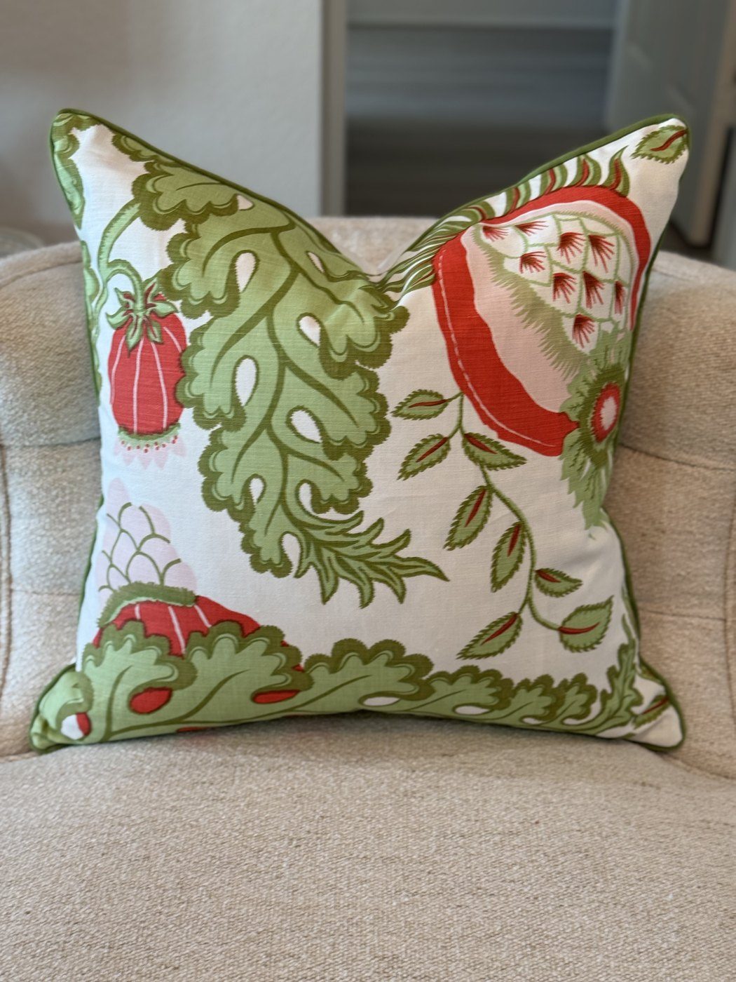 Carnival red and green botanical pillow with green piping on armchair