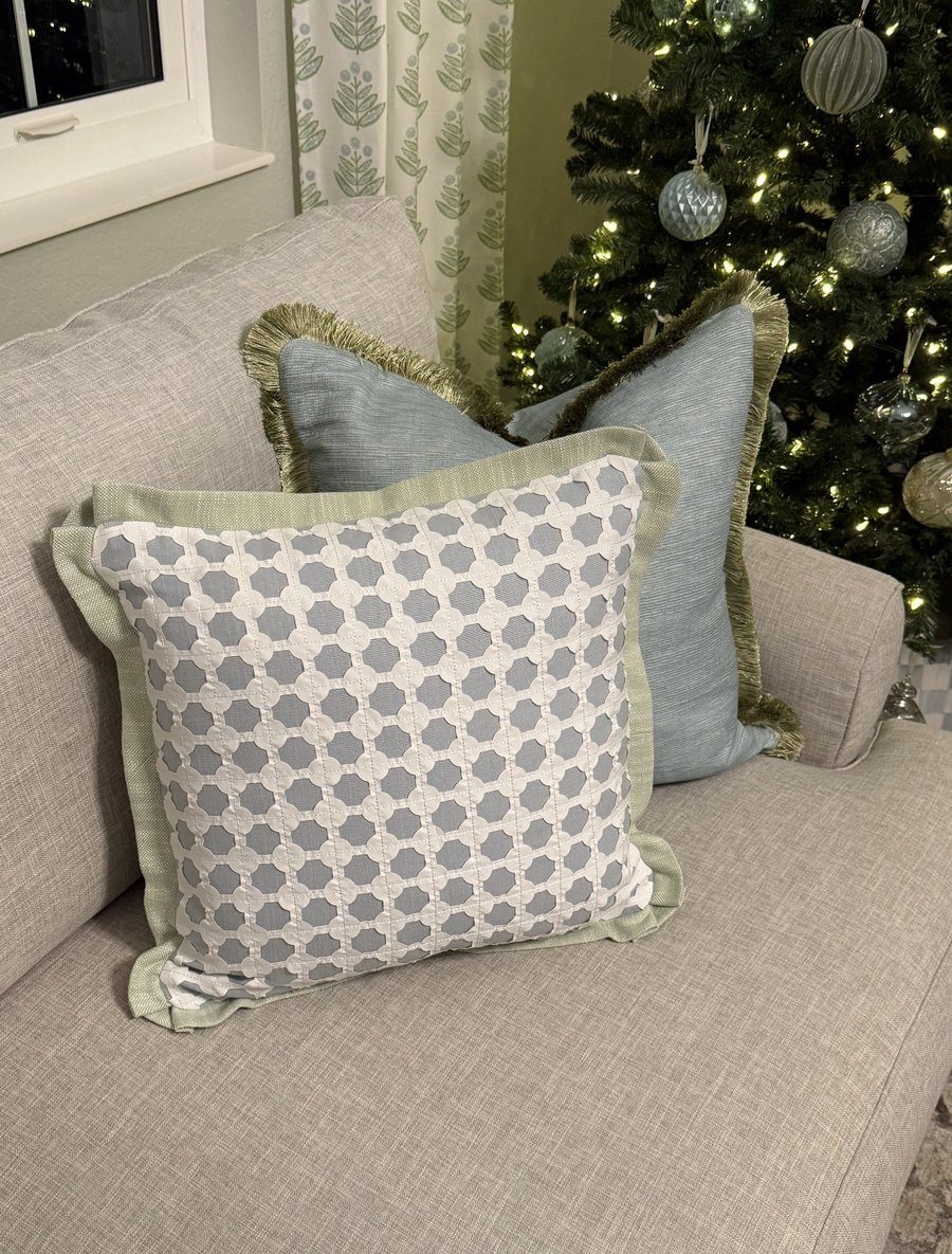 Cothay lattice pillow with sage flange styled on sofa by Christmas tree with blue fringe pillow