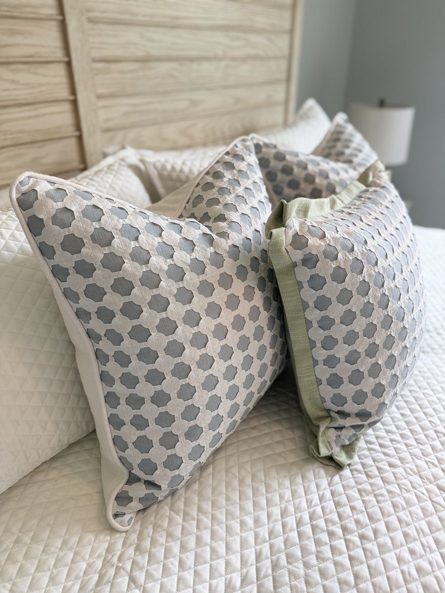 Pair of Cothay soft blue lattice pillows styled on bed, one with white piping and one with sage flange
