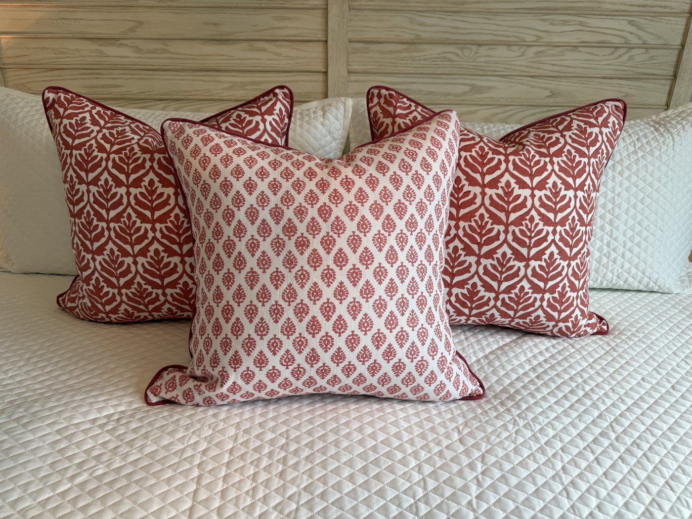 Devi coral block print pillow with coordinating coral leaf pillows on bed