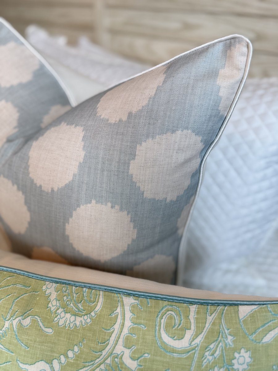 Duckie soft blue ikat dot pillow corner close-up with ivory piping on bed