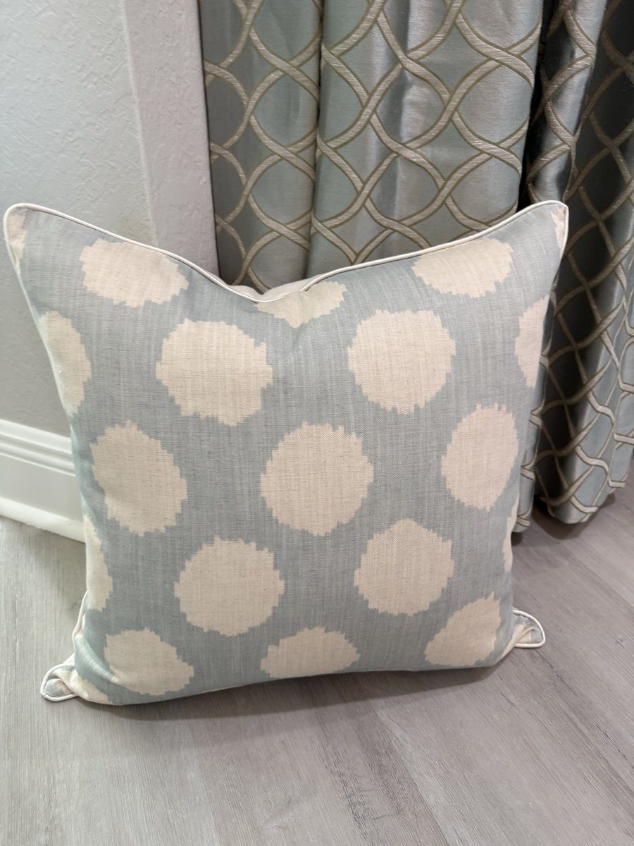 Duckie soft blue Andrew Martin ikat dot pillow styled against drapery