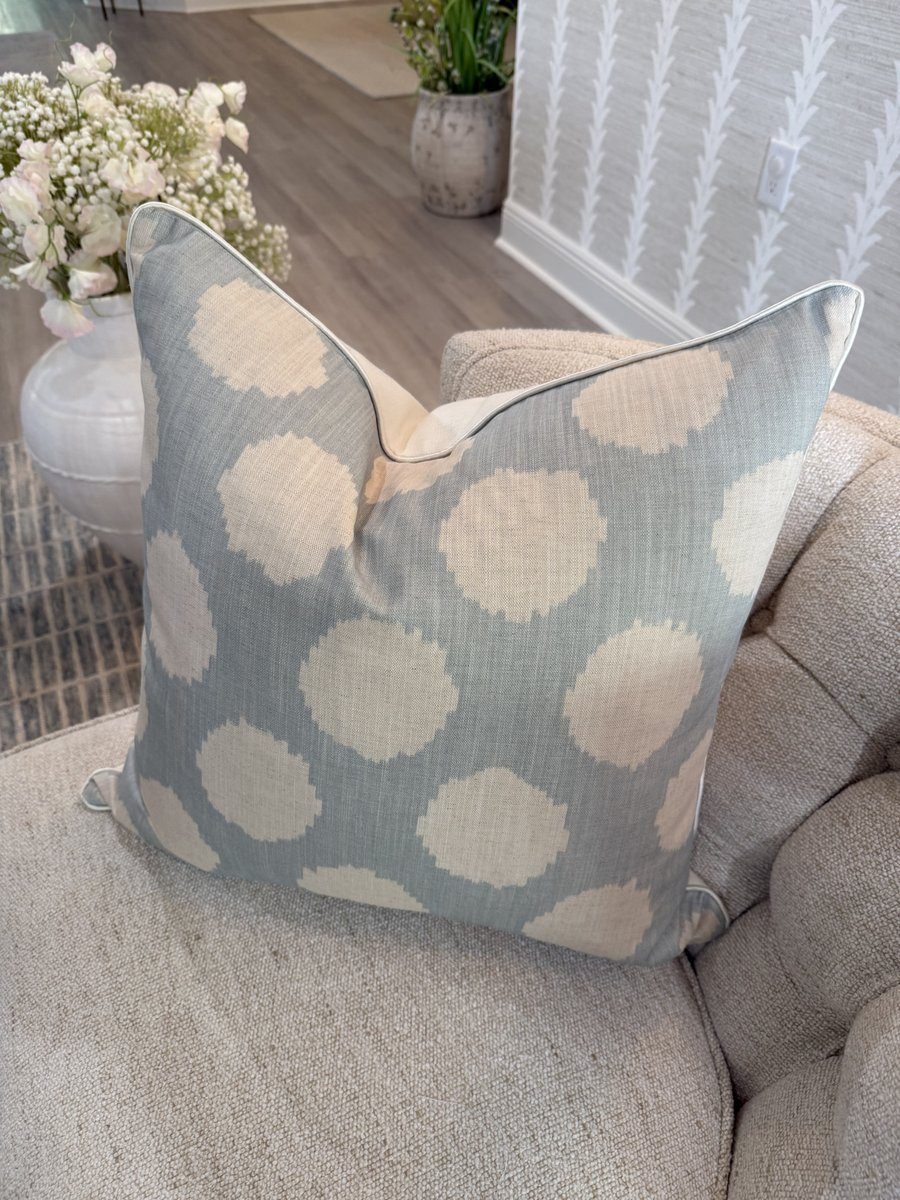 Duckie soft blue Andrew Martin ikat dot pillow styled on tufted armchair in living room