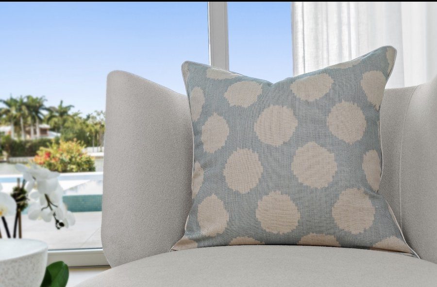 Duckie soft blue ikat dot pillow on armchair with pool and palm view