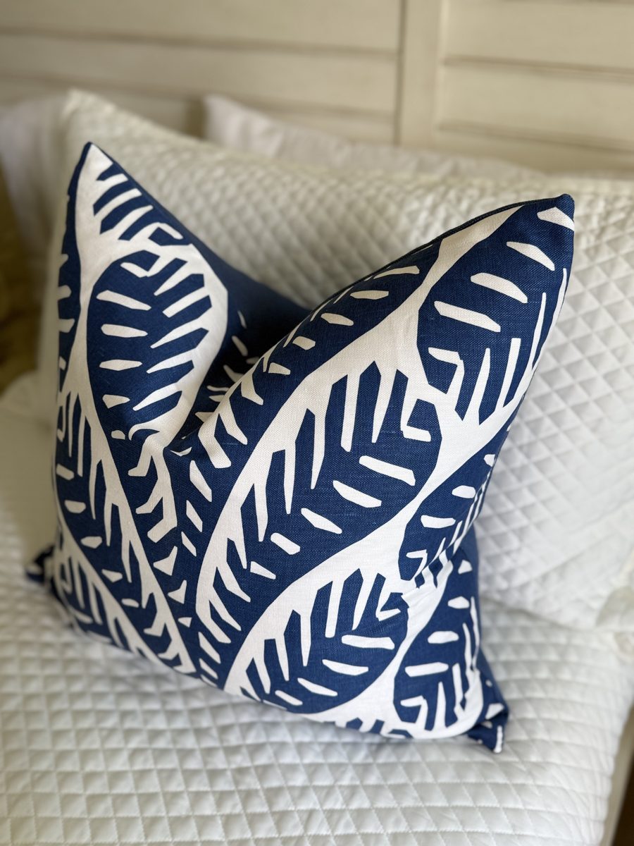 Ginger navy palm pillow angled view on bed