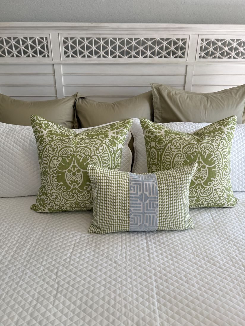 Greenwich houndstooth lumbar pillow styled on bed with green pillows