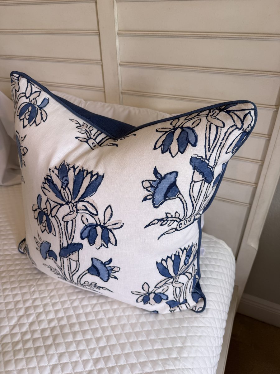 Heidi pillow angled view with navy linen back and piping on bed