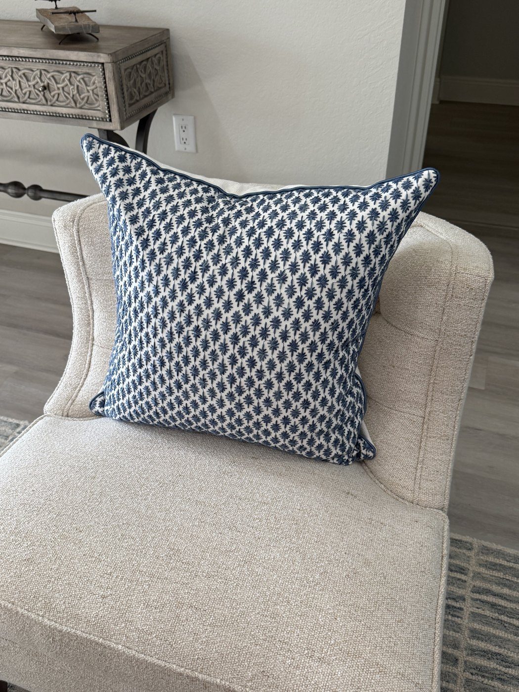 Kristin embroidered navy pillow with navy piping on armchair