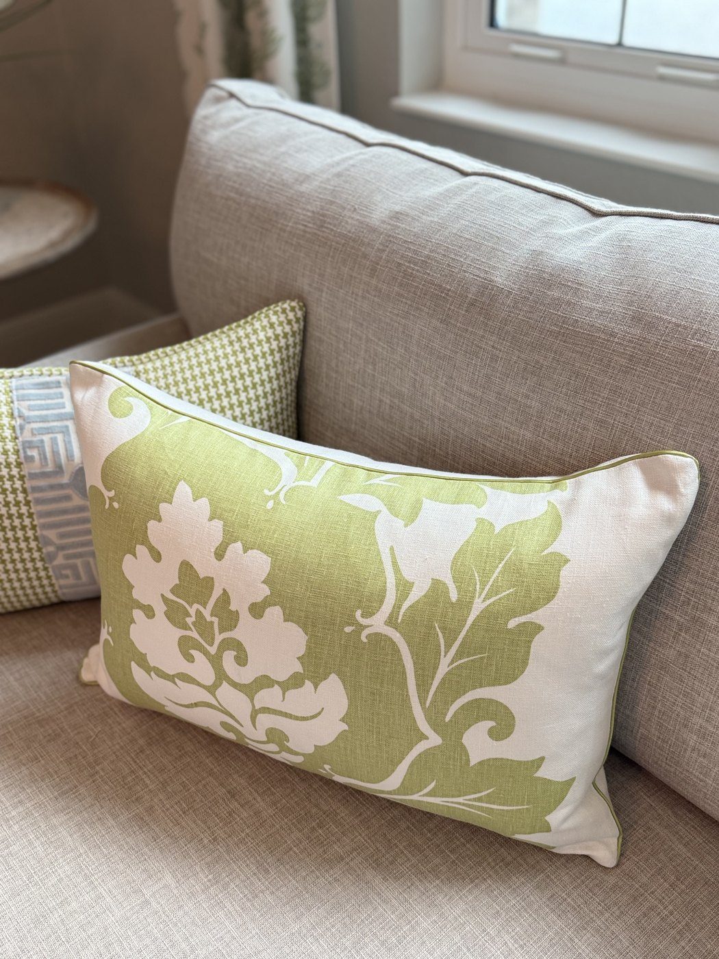 Margate green damask pillow with green piping angled on sofa