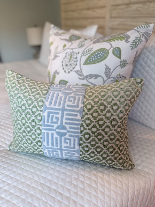 Green lumbar with Labyrinth stripe styled with floral pillow on bed
