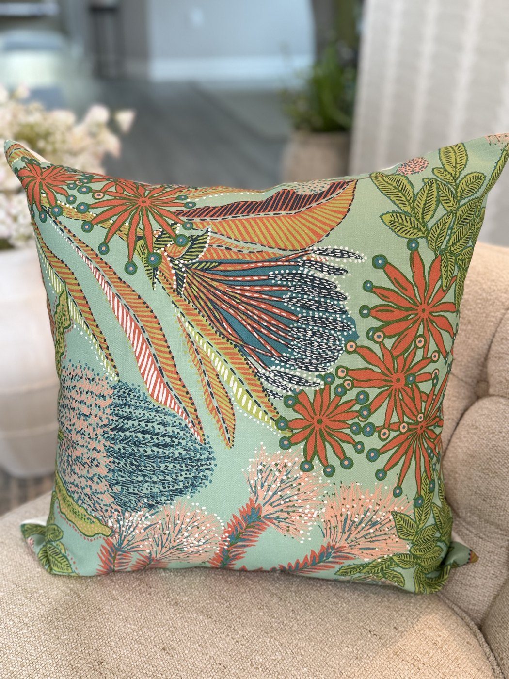 Protea pillow with coral and teal botanical print styled on armchair