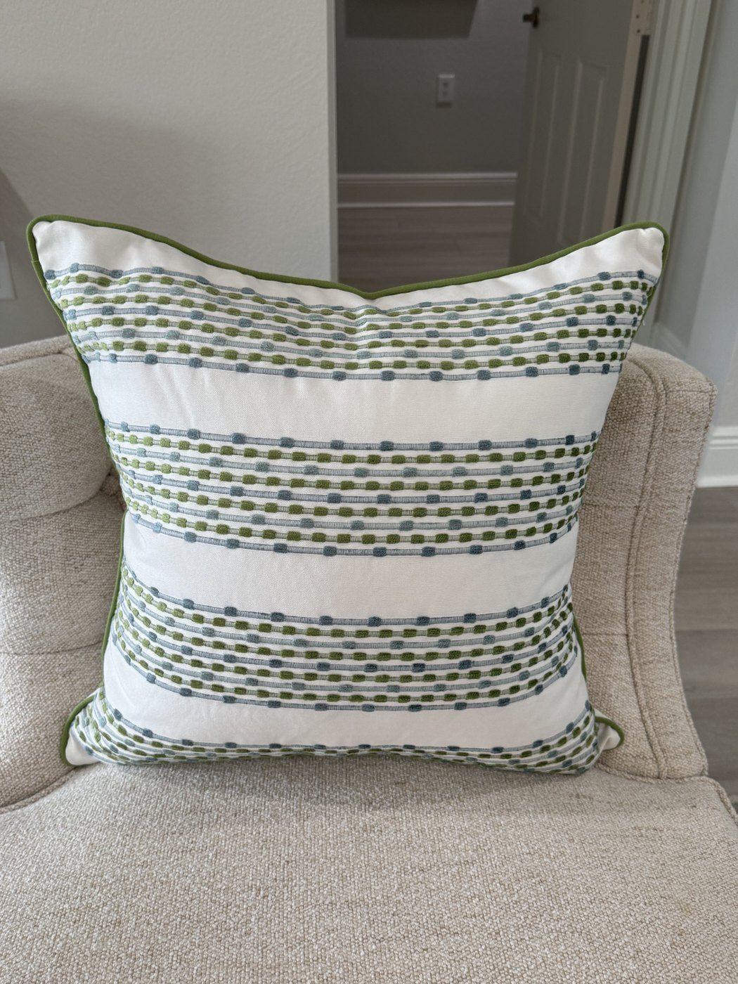 Sherri's Stripes embroidered green and blue stripe pillow with green piping on armchair