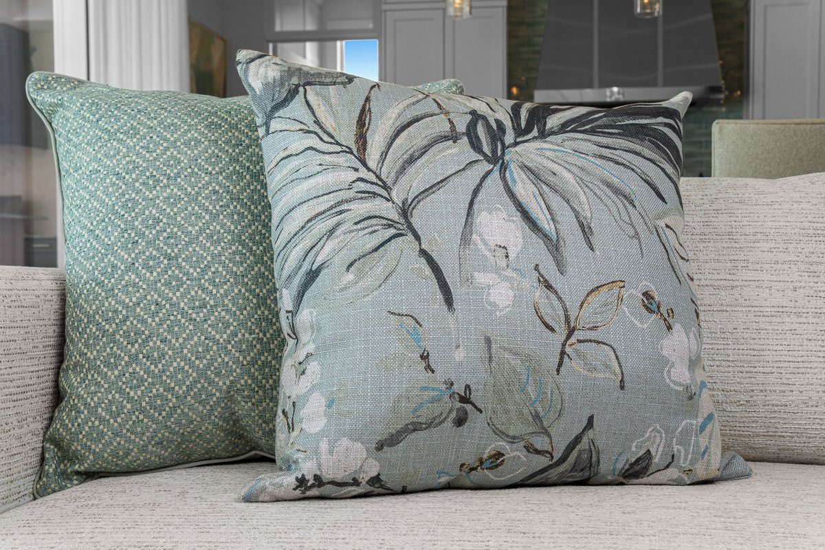 Takara botanical pillow styled on sofa with teal companion pillow