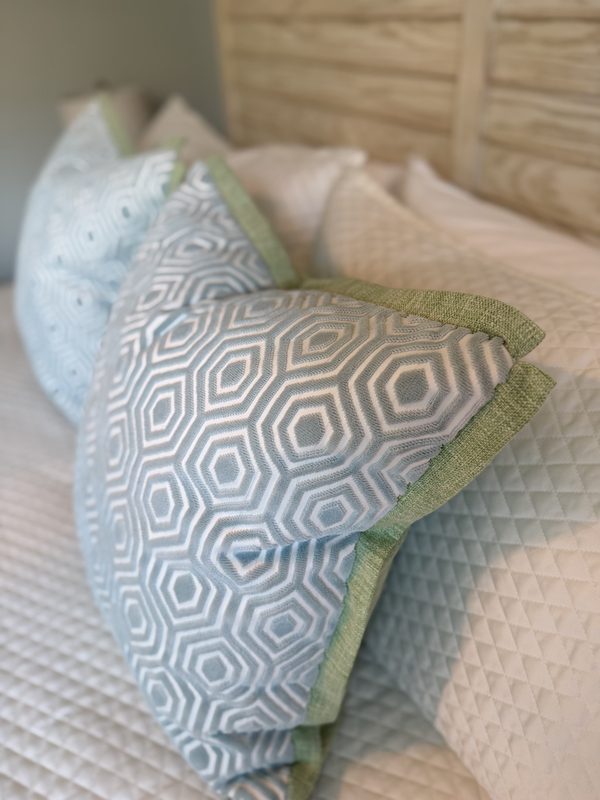 Hexagon velvet pillow with green flange styled on bed